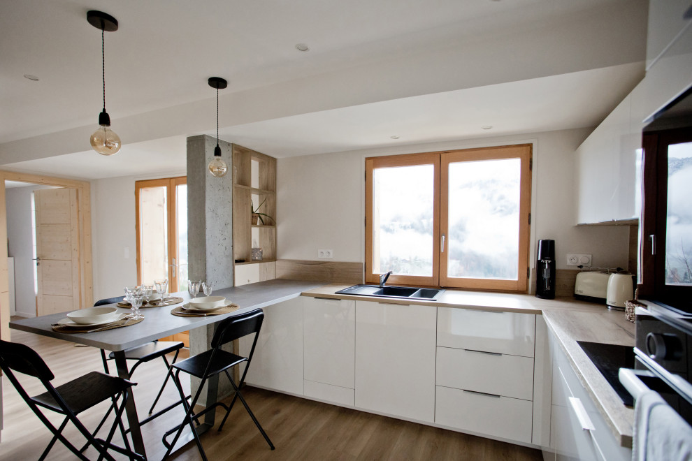 Large contemporary u-shaped open plan kitchen in Other with a single-bowl sink, beaded cabinets, white cabinets, laminate countertops, brown splashback, wood splashback, black appliances, light hardwood flooring, an island, brown floors and brown worktops.
