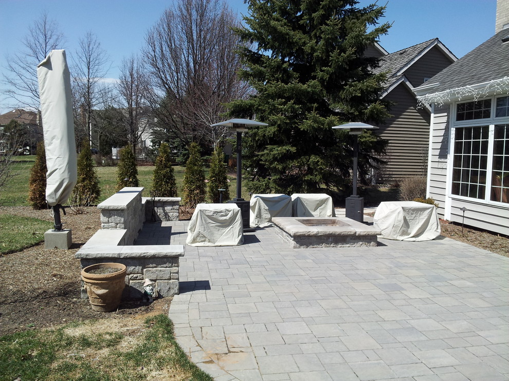 This is an example of a mid-sized contemporary backyard patio in Chicago with a fire feature and natural stone pavers.