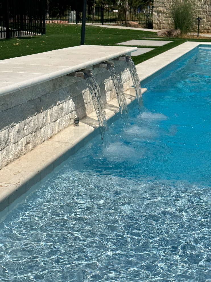 Ejemplo de piscina minimalista grande rectangular en patio trasero con adoquines de hormigón