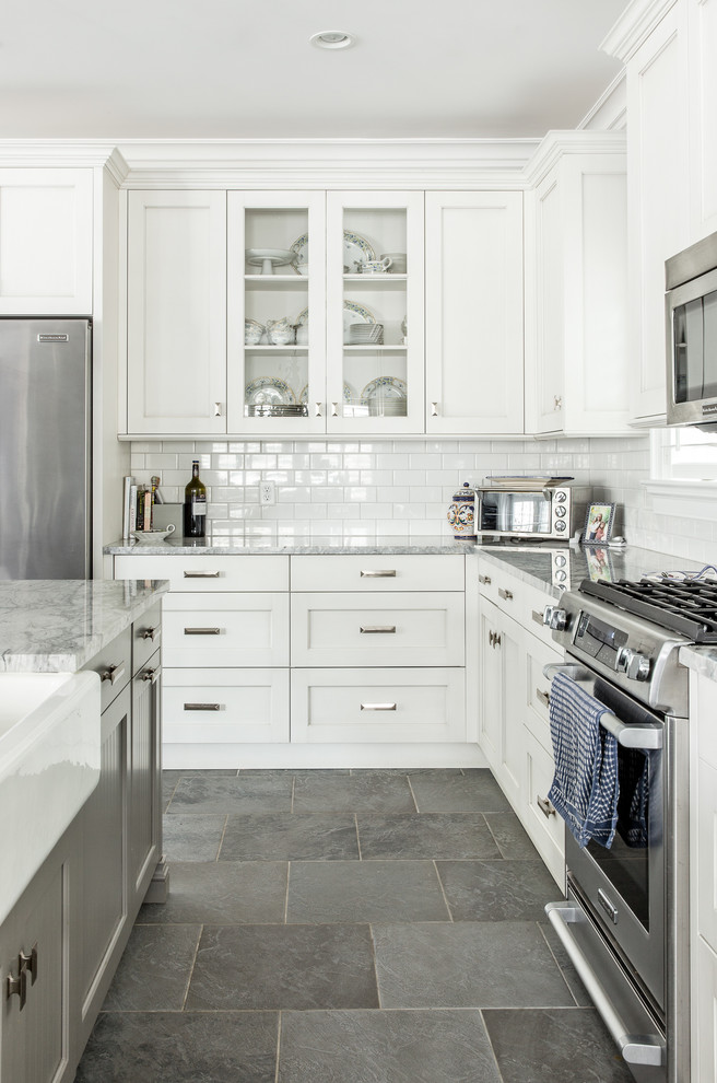 Inspiration for a large traditional l-shaped open plan kitchen in New York with a farmhouse sink, recessed-panel cabinets, white cabinets, granite benchtops, white splashback, subway tile splashback, stainless steel appliances, slate floors and with island.