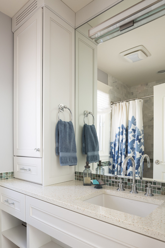 Photo of a small transitional kids bathroom in Chicago with an undermount sink, recessed-panel cabinets, white cabinets, recycled glass benchtops, an alcove tub, a shower/bathtub combo, a one-piece toilet, blue tile, glass tile, grey walls and limestone floors.
