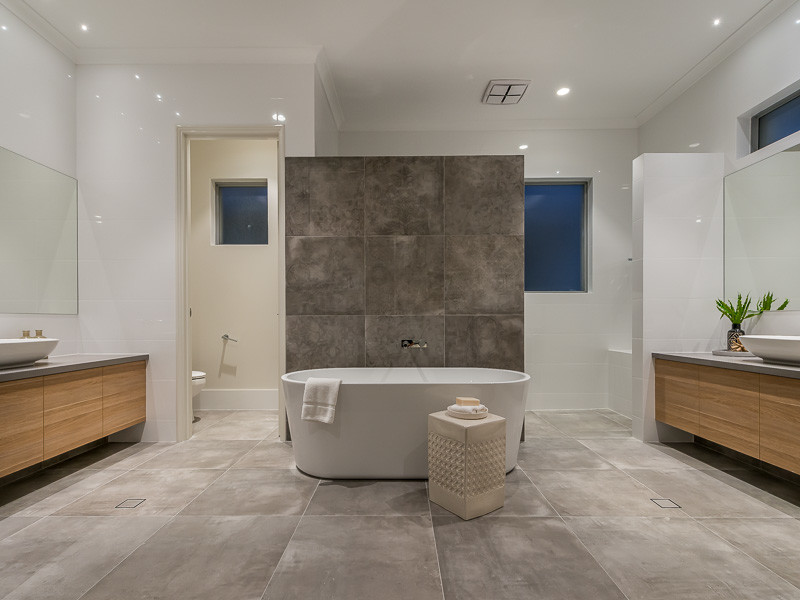 This is an example of an expansive contemporary master bathroom in Perth with flat-panel cabinets, light wood cabinets, a freestanding tub, an open shower, a wall-mount toilet, white tile, porcelain tile, white walls, porcelain floors, a vessel sink, engineered quartz benchtops, grey floor and a hinged shower door.