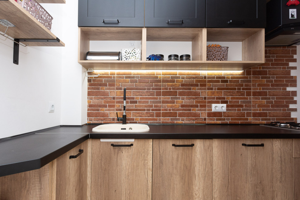 Photo of a small rural l-shaped kitchen in Other with a belfast sink, raised-panel cabinets, grey cabinets, wood worktops, black splashback, brick splashback, black appliances, ceramic flooring, no island and brown floors.