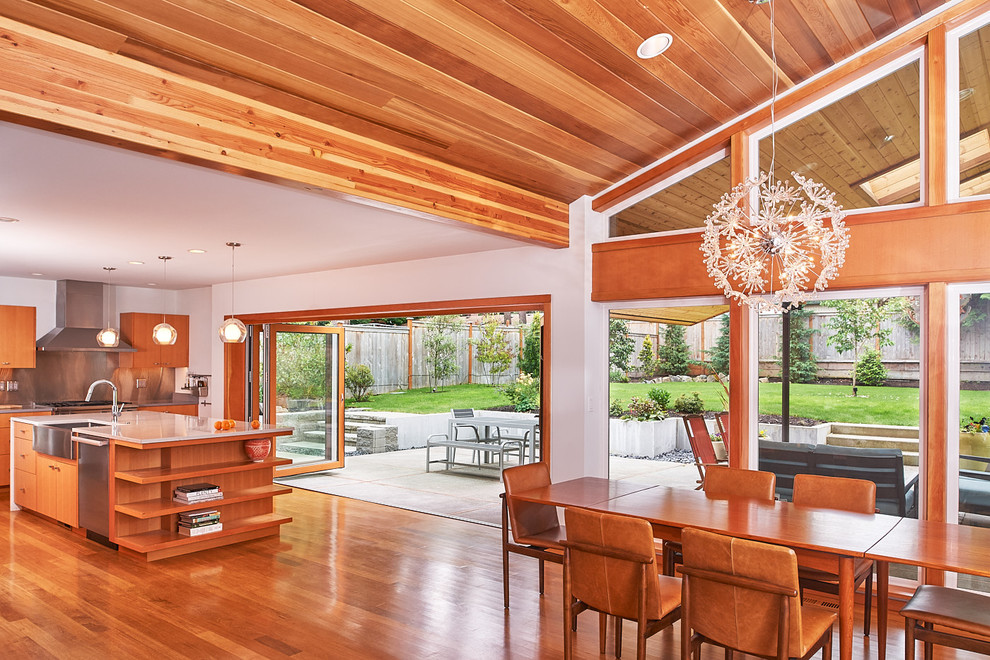 Expansive midcentury open plan dining in Seattle with white walls, medium hardwood floors and brown floor.