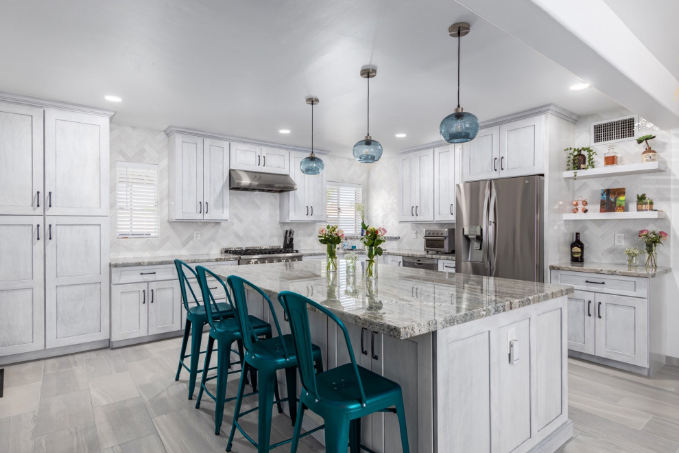 Example of a transitional l-shaped kitchen design in Phoenix with a single-bowl sink, shaker cabinets, white cabinets, granite countertops, white backsplash and stainless steel appliances