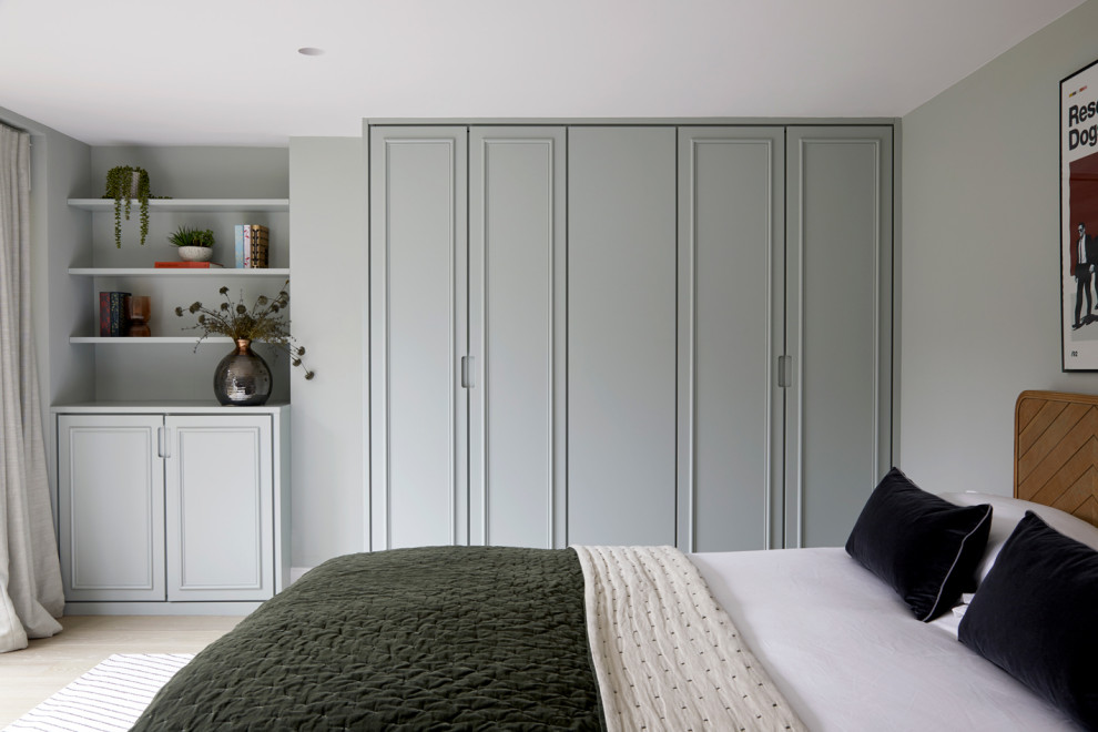 Großes Modernes Gästezimmer mit grüner Wandfarbe, hellem Holzboden und beigem Boden in London