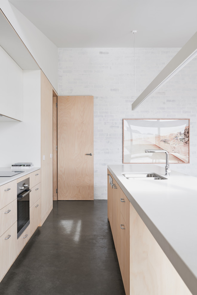 Inspiration for a contemporary galley open plan kitchen in Melbourne with a double-bowl sink, flat-panel cabinets, light wood cabinets, stainless steel appliances, concrete floors, with island, white splashback, ceramic splashback and grey floor.