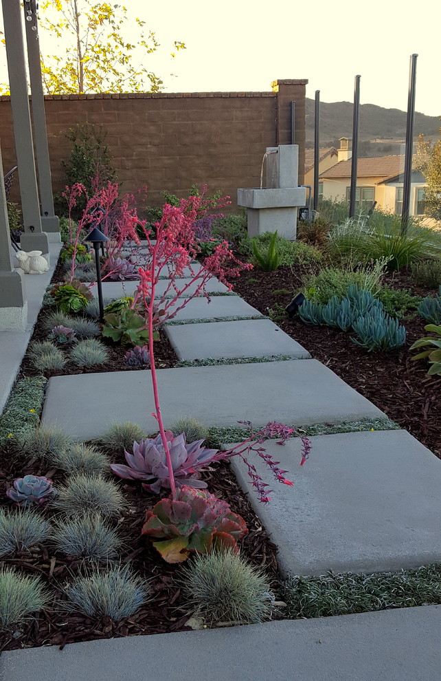 This is an example of a small country backyard full sun xeriscape in Los Angeles with a vegetable garden and concrete pavers.