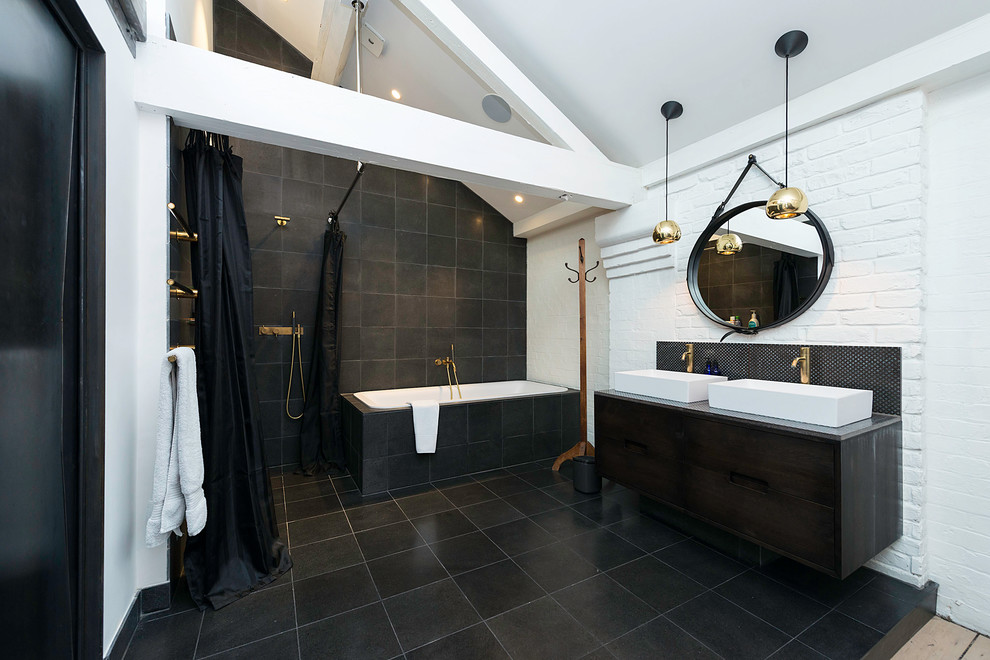 Large industrial bathroom in London with flat-panel cabinets, dark wood cabinets, a drop-in tub, an open shower, black tile, white walls, a shower curtain, ceramic floors and a vessel sink.