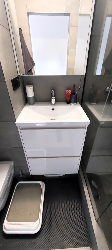 Стильный дизайн: маленькая серо-белая ванная комната в современном стиле с плоскими фасадами, белыми фасадами, душем в нише, инсталляцией, серой плиткой, керамогранитной плиткой, серыми стенами, полом из керамогранита, душевой кабиной, накладной раковиной, серым полом, шторкой для ванной, гигиеническим душем, тумбой под одну раковину и подвесной тумбой для на участке и в саду - последний тренд