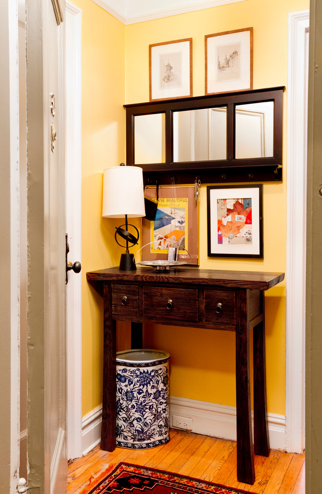 Entryway - small traditional light wood floor entryway idea in New York with yellow walls and a white front door