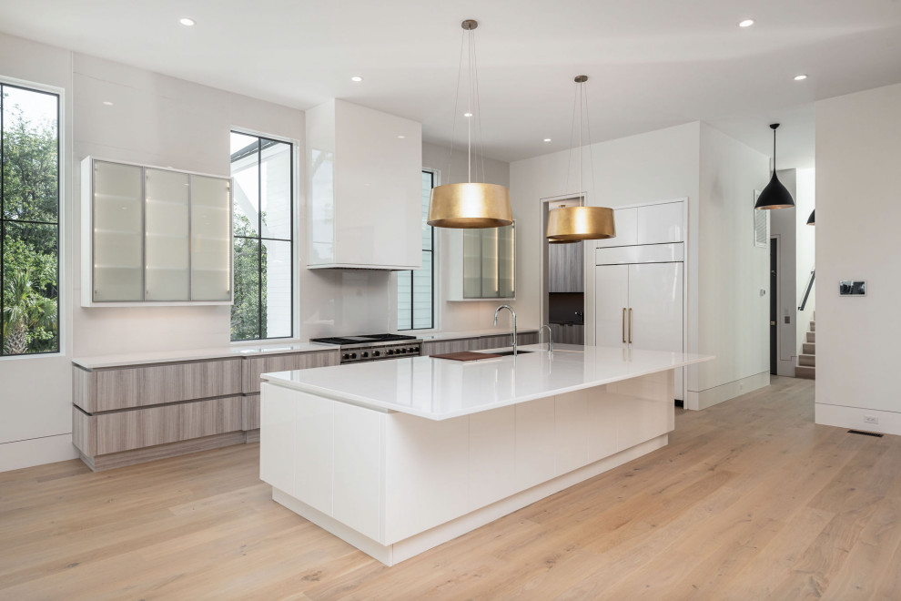Inspiration for a large modern l-shaped eat-in kitchen in Charleston with a double-bowl sink, recessed-panel cabinets, white cabinets, quartz benchtops, white splashback, porcelain splashback, panelled appliances, light hardwood floors, with island, beige floor and white benchtop.