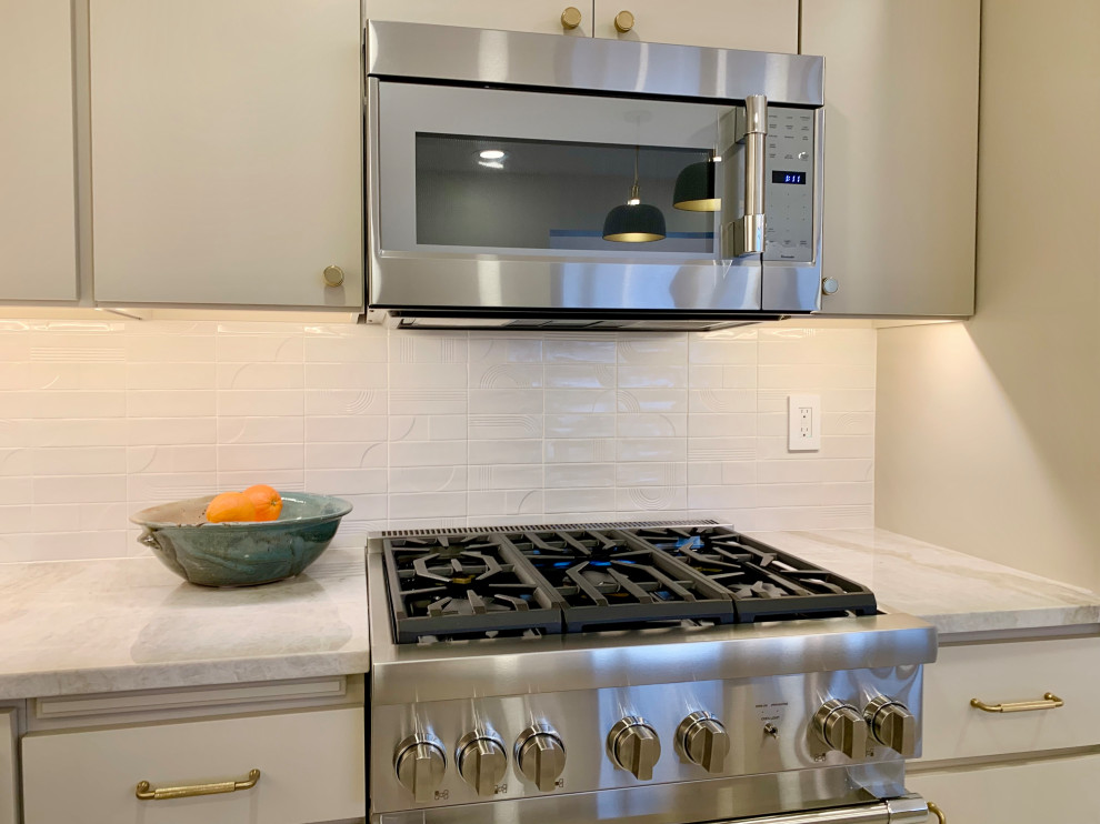 Large minimalist l-shaped porcelain tile and beige floor kitchen pantry photo with a single-bowl sink, flat-panel cabinets, beige cabinets, quartzite countertops, white backsplash, porcelain backsplash, stainless steel appliances, an island and beige countertops