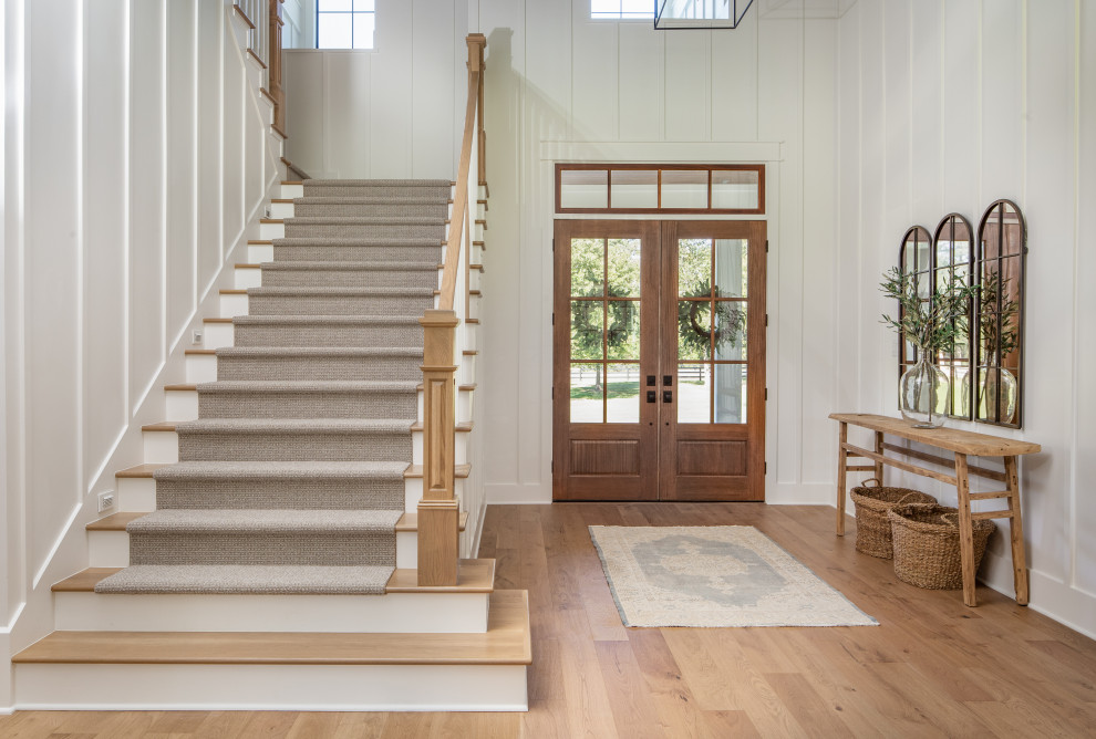Photo of a large country foyer in Houston with white walls, medium hardwood floors, a double front door, a dark wood front door, brown floor and wood walls.