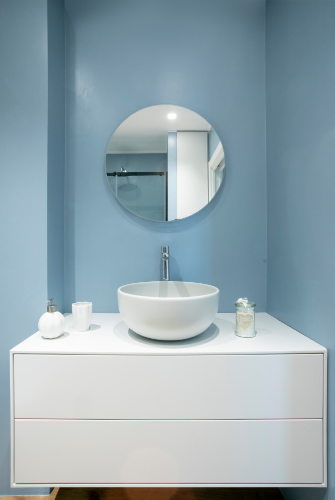 Idéer för att renovera ett litet funkis grå grått badrum med dusch, med släta luckor, grå skåp, en kantlös dusch, en vägghängd toalettstol, blå kakel, porslinskakel, blå väggar, ljust trägolv, ett fristående handfat, träbänkskiva, beiget golv och dusch med skjutdörr
