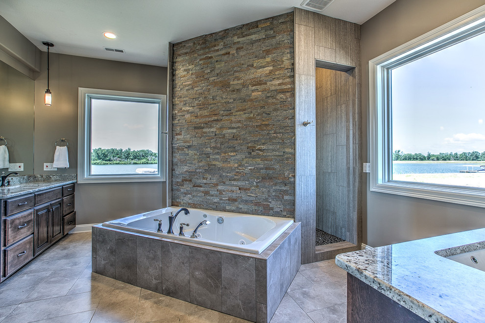 Large transitional master bathroom in Omaha with raised-panel cabinets, dark wood cabinets, a hot tub, an alcove shower, beige tile, porcelain tile, brown walls, porcelain floors, a drop-in sink and granite benchtops.