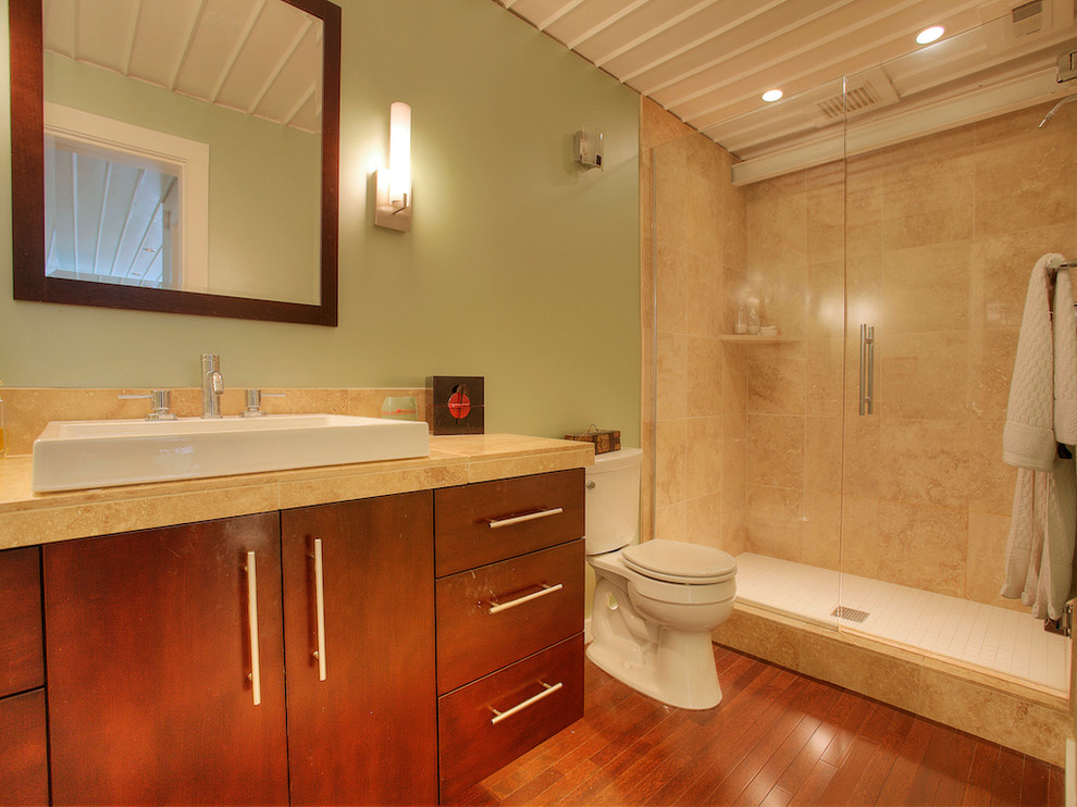 Photo of a mid-sized industrial master bathroom in Seattle with a vessel sink, flat-panel cabinets, dark wood cabinets, limestone benchtops, an alcove shower, beige tile, stone tile, green walls and dark hardwood floors.