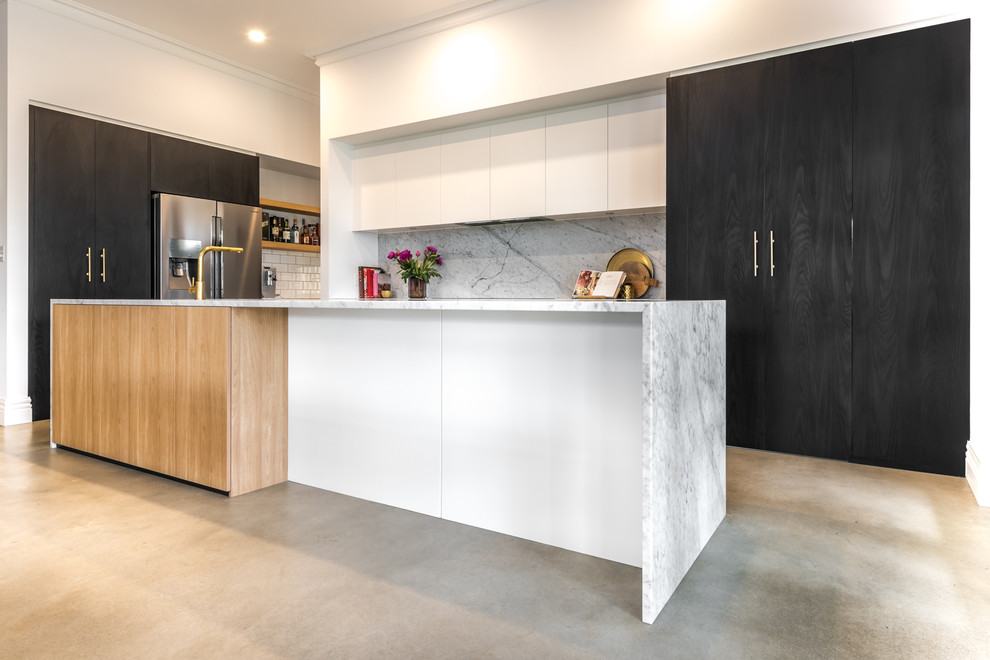 Inspiration for a large contemporary galley kitchen pantry in Adelaide with an undermount sink, flat-panel cabinets, black cabinets, marble benchtops, white splashback, marble splashback, stainless steel appliances, concrete floors, with island and brown floor.