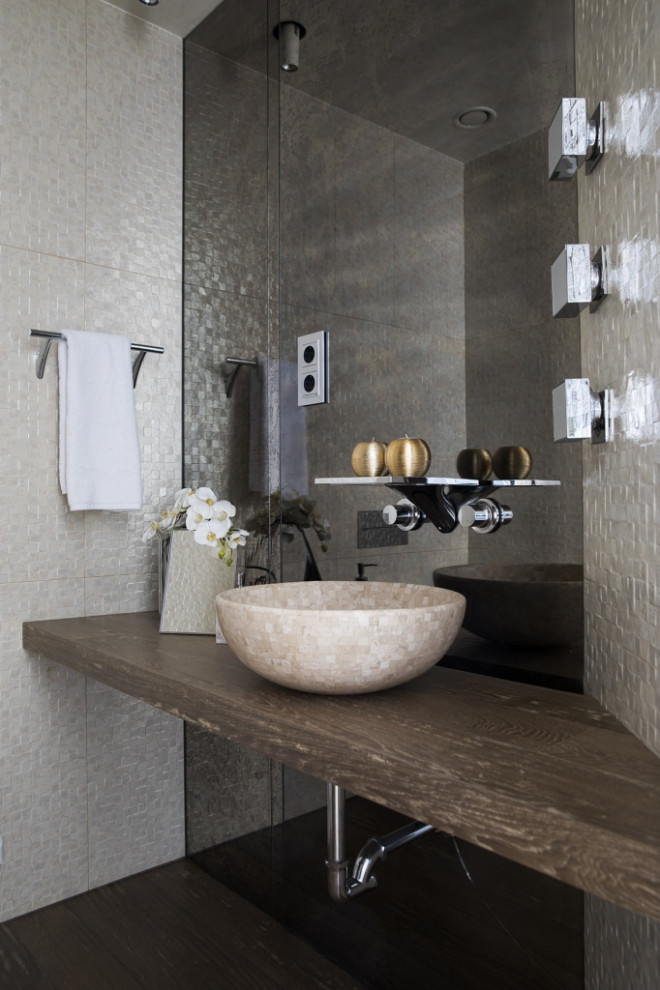 This is an example of a mid-sized contemporary powder room in Madrid with open cabinets, medium wood cabinets, glass sheet wall, dark hardwood floors, a vessel sink, wood benchtops, brown floor and brown benchtops.