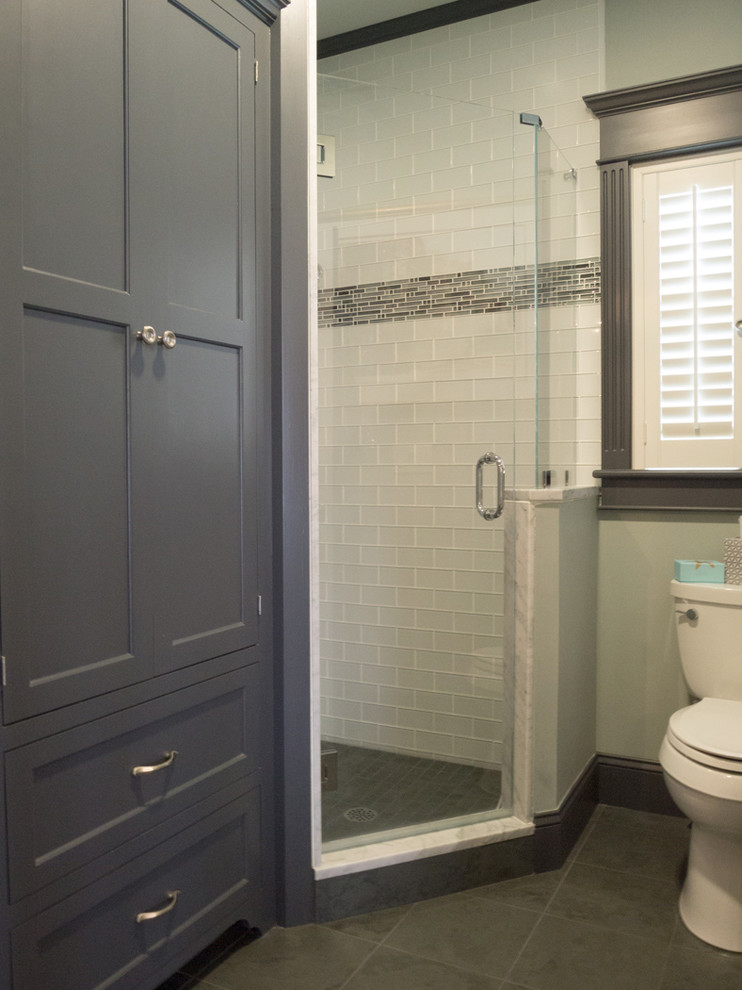 Photo of a mid-sized traditional bathroom in Providence with recessed-panel cabinets, black cabinets, a corner shower, a one-piece toilet, black and white tile, glass tile, blue walls, ceramic floors, an integrated sink and marble benchtops.