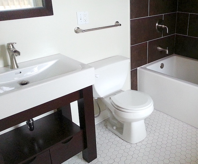 This is an example of a small contemporary 3/4 bathroom in Chicago with open cabinets, dark wood cabinets, an alcove tub, a shower/bathtub combo, a two-piece toilet, brown tile, white tile, porcelain tile, white walls, porcelain floors, an integrated sink and solid surface benchtops.