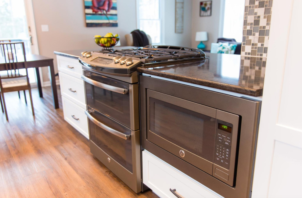 Inspiration for a mid-sized transitional galley medium tone wood floor and brown floor eat-in kitchen remodel with an undermount sink, shaker cabinets, white cabinets, marble countertops, metallic backsplash, mosaic tile backsplash, stainless steel appliances and a peninsula