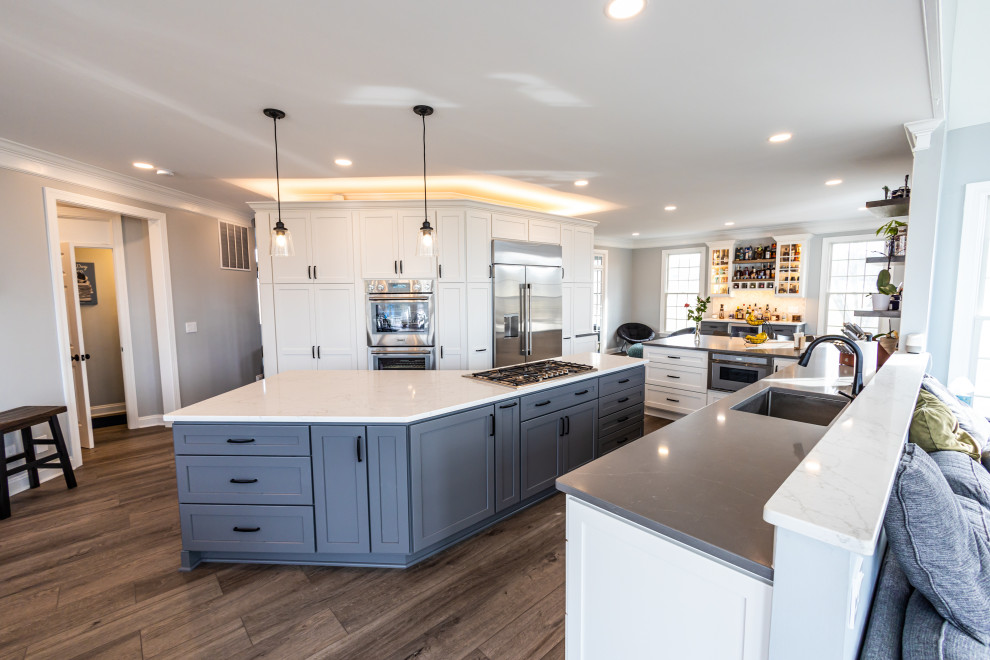 Large transitional vinyl floor and brown floor kitchen photo in Baltimore with an undermount sink, shaker cabinets, white backsplash, porcelain backsplash, stainless steel appliances, an island and white countertops