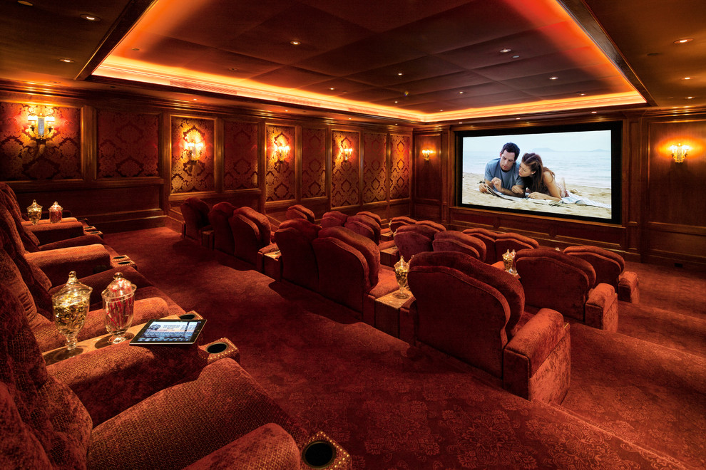 Photo of a traditional enclosed home theatre in Los Angeles with red walls, carpet, a projector screen and red floor.