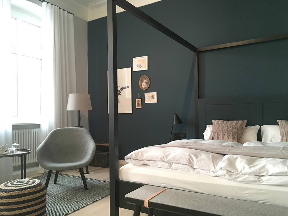 Photo of a mid-sized scandinavian bedroom in Berlin with black walls and light hardwood floors.