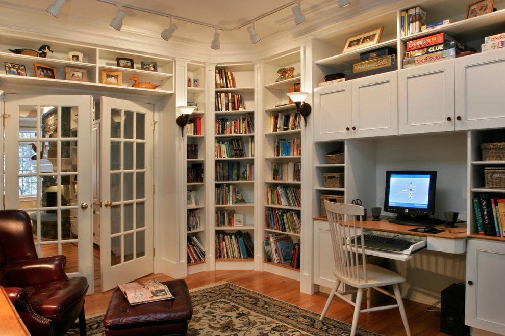 Inspiration for a mid-sized traditional home office in Boston with white walls, light hardwood floors and a built-in desk.