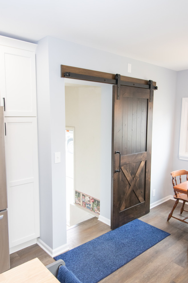 Mid-sized transitional galley vinyl floor and brown floor eat-in kitchen photo with an undermount sink, flat-panel cabinets, white cabinets, quartzite countertops, stainless steel appliances, an island and white countertops
