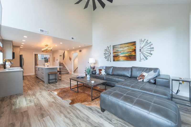 Photo of a mid-sized modern formal open concept living room in Salt Lake City with beige walls, laminate floors, a standard fireplace, a metal fireplace surround, a wall-mounted tv, multi-coloured floor and vaulted.