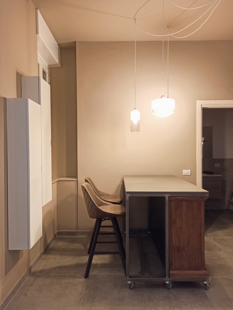 На фото: кухня-гостиная среднего размера в современном стиле с плоскими фасадами, белыми фасадами, бетонным полом и серым полом с