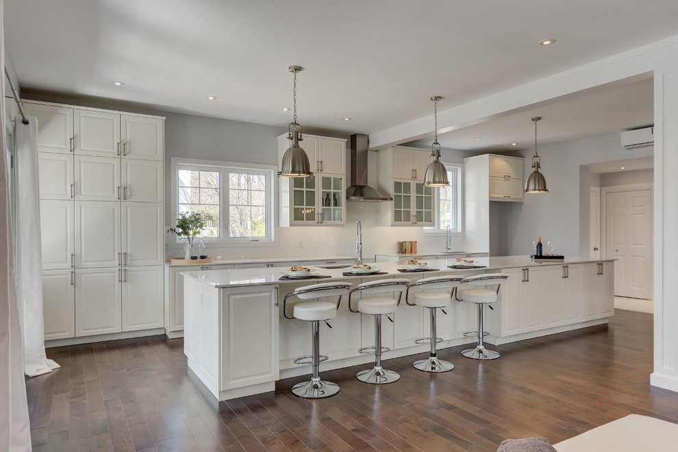 Inspiration for a large contemporary single-wall eat-in kitchen in Montreal with an undermount sink, raised-panel cabinets, white cabinets, quartz benchtops, white splashback, subway tile splashback, medium hardwood floors, with island and brown floor.