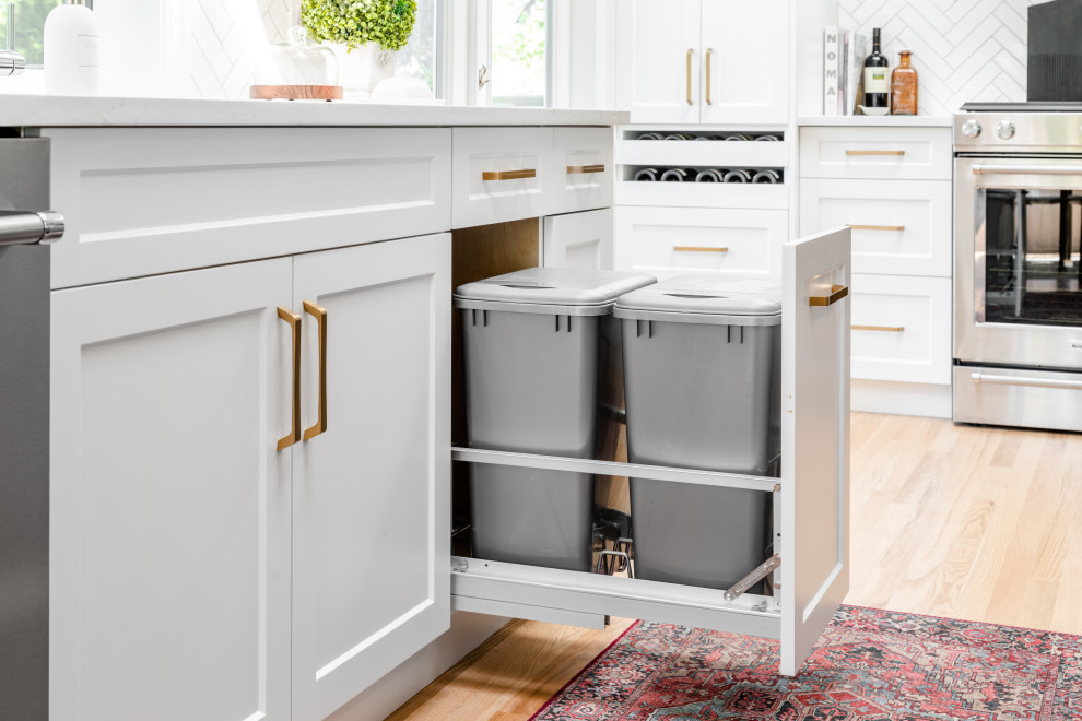 Inspiration for a large transitional l-shaped light wood floor and beige floor open concept kitchen remodel in Vancouver with an undermount sink, recessed-panel cabinets, white cabinets, quartz countertops, white backsplash, ceramic backsplash, stainless steel appliances, an island and white countertops