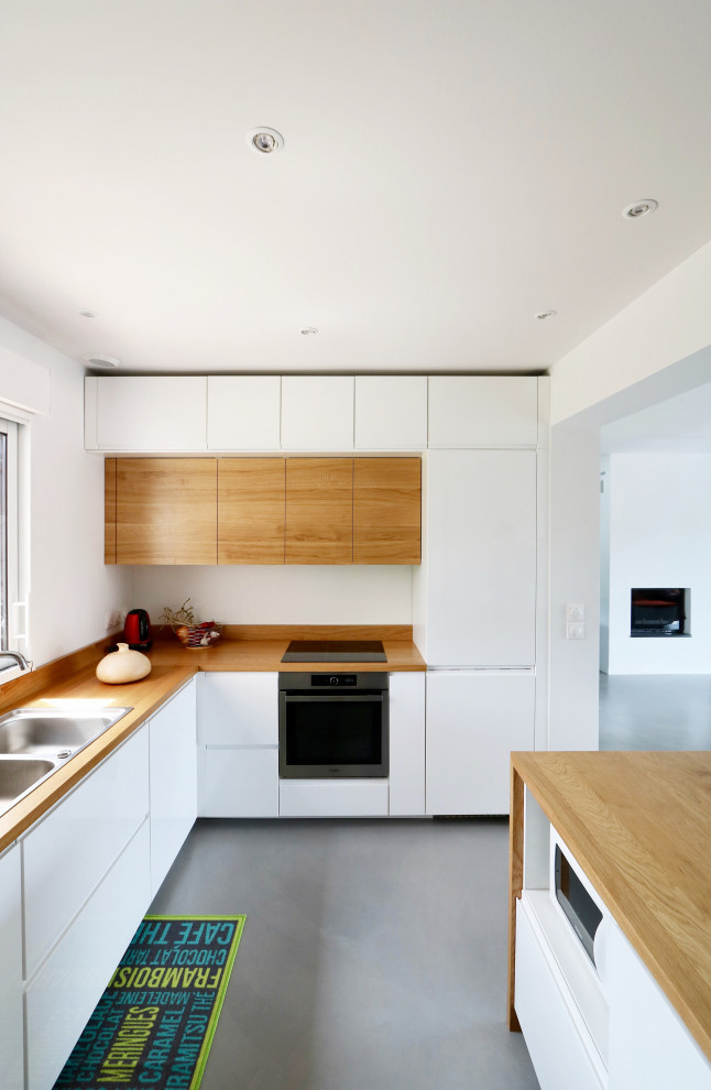 Mid-sized contemporary single-wall open plan kitchen in Montpellier with a single-bowl sink, white cabinets, wood benchtops, brown splashback, timber splashback, no island, grey floor and brown benchtop.