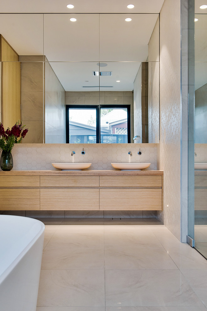 Inspiration for a large contemporary master bathroom in Adelaide with flat-panel cabinets, light wood cabinets, a freestanding tub, white tile, porcelain floors, a vessel sink, wood benchtops, beige floor, beige benchtops, a double vanity and a floating vanity.