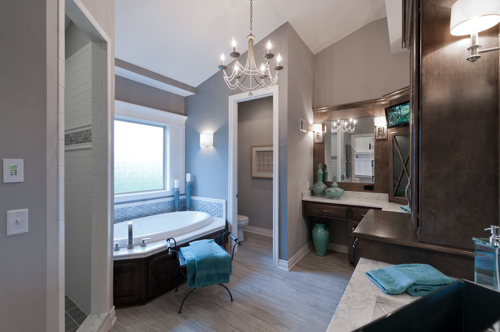 This is an example of a mid-sized transitional master wet room bathroom in Kansas City with flat-panel cabinets, dark wood cabinets, a drop-in tub, a two-piece toilet, beige tile, marble, grey walls, medium hardwood floors, an undermount sink, marble benchtops, grey floor and an open shower.