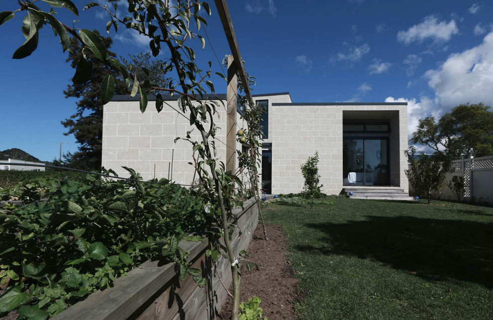 This is an example of a large contemporary two-storey beige exterior in Hamilton with stone veneer and a flat roof.