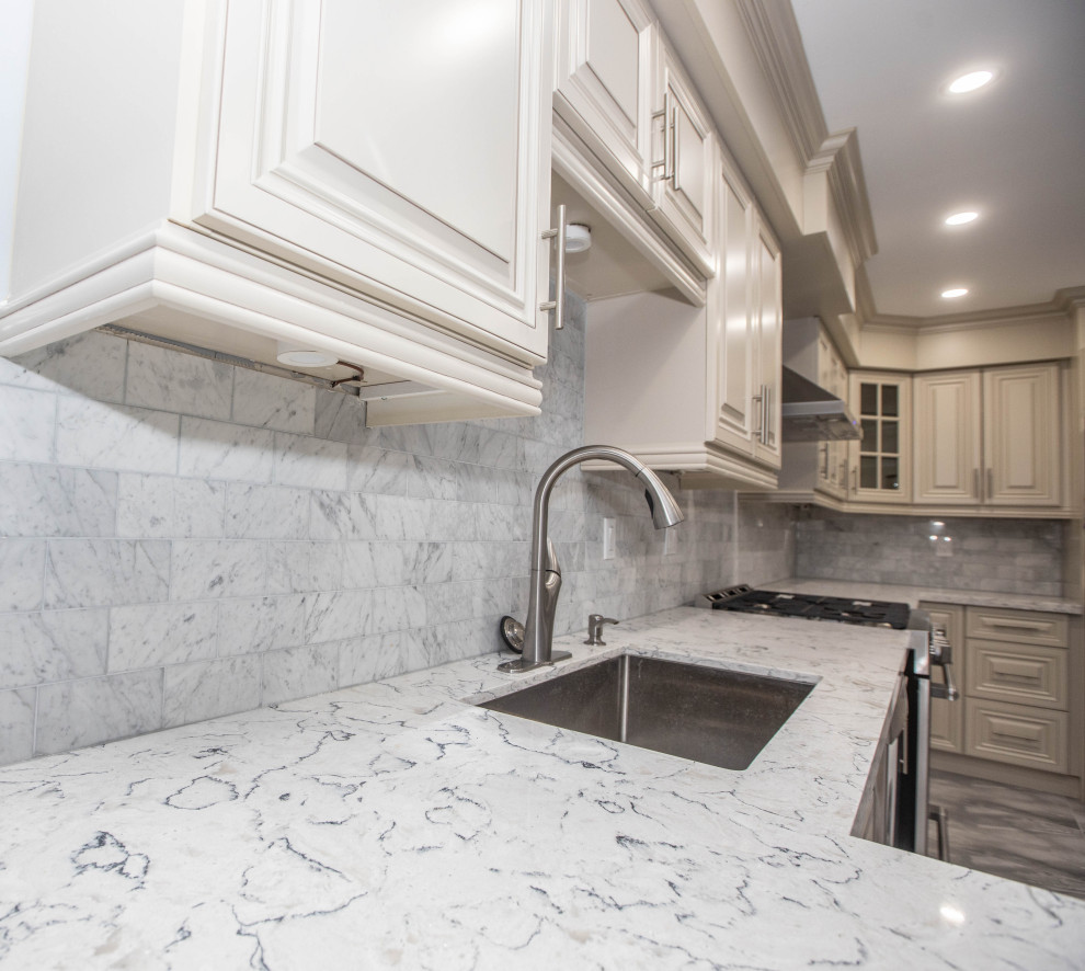 Photo of a mid-sized transitional l-shaped eat-in kitchen in Toronto with raised-panel cabinets, white cabinets, quartz benchtops, grey splashback, ceramic splashback, stainless steel appliances, a peninsula and white benchtop.