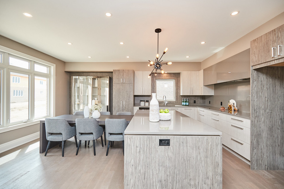 Large transitional l-shaped medium tone wood floor and gray floor eat-in kitchen photo with an undermount sink, flat-panel cabinets, gray cabinets, quartzite countertops, gray backsplash, stainless steel appliances, an island and gray countertops
