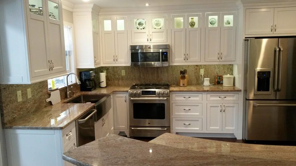 Mid-sized transitional u-shaped medium tone wood floor and brown floor eat-in kitchen photo with shaker cabinets, white cabinets, granite countertops, brown backsplash, stone slab backsplash, white appliances, a peninsula and a farmhouse sink