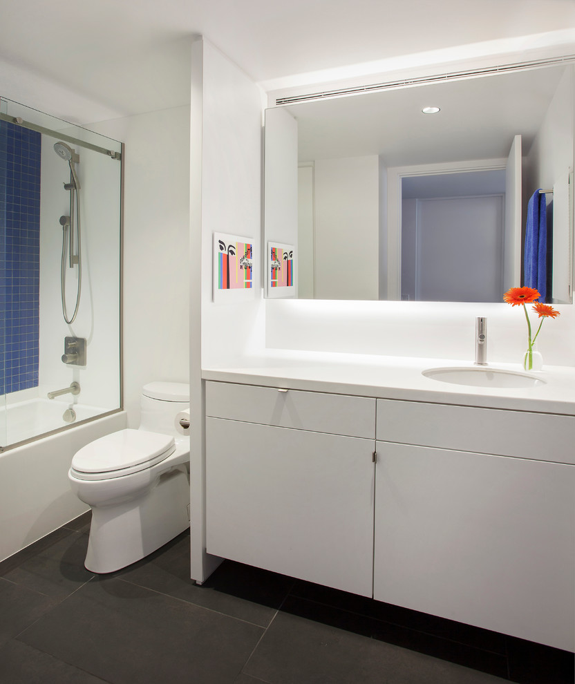 Photo of a mid-sized contemporary bathroom in Chicago with flat-panel cabinets, white cabinets, solid surface benchtops, blue tile, glass tile, white walls and porcelain floors.