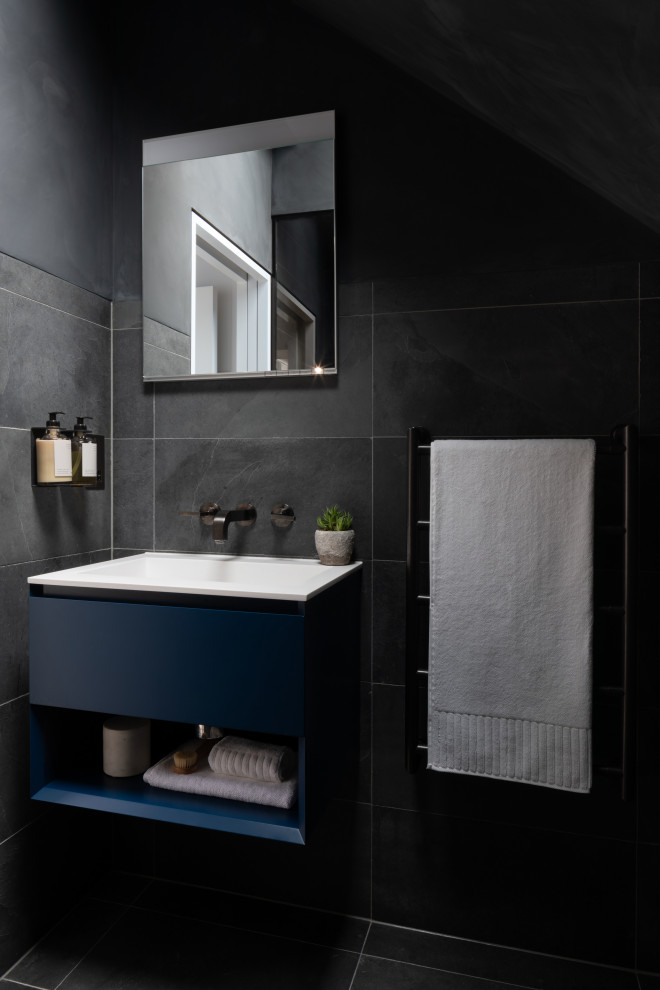 Small contemporary 3/4 wet room bathroom in London with flat-panel cabinets, blue cabinets, a wall-mount toilet, black tile, porcelain tile, a drop-in sink, solid surface benchtops, black floor, an open shower, white benchtops, a single vanity and a freestanding vanity.