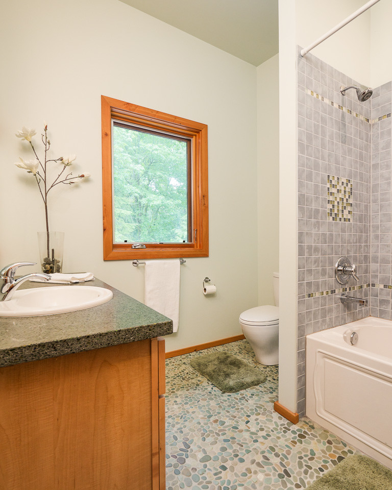 Mid-sized modern kids bathroom in Seattle with a drop-in sink, medium wood cabinets, an alcove tub, a shower/bathtub combo, a one-piece toilet and mosaic tile.