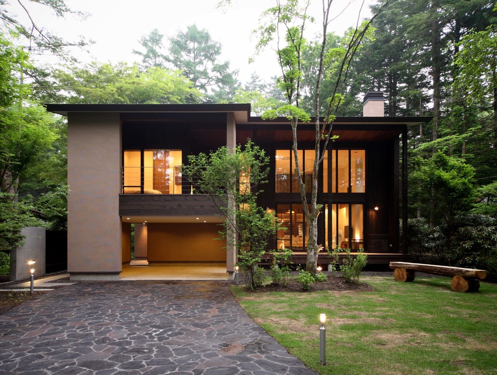 Photo of a large modern two-storey brown house exterior in Other with wood siding, a hip roof and a metal roof.