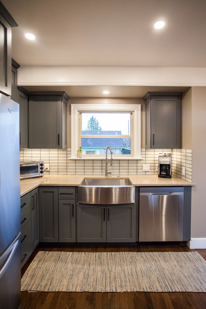 Example of a small transitional l-shaped dark wood floor and brown floor open concept kitchen design in Seattle with a farmhouse sink, shaker cabinets, gray cabinets, stainless steel appliances, an island, granite countertops, white backsplash, porcelain backsplash and beige countertops