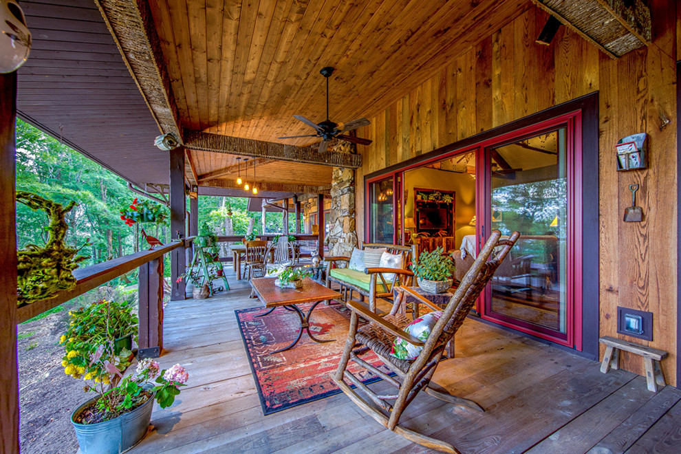 Large mountain style back porch photo with a fireplace, decking and a roof extension