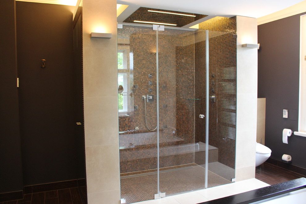 Badezimmer With Whirlpool, bodengleicher Dusche, Wandtoilette, braunen Fliesen, Mosaikfliesen, brauner Wandfarbe, dunklem Holzboden, Wandwaschbecken, braunem Boden and Falttür-Duschabtrennung in Berlin