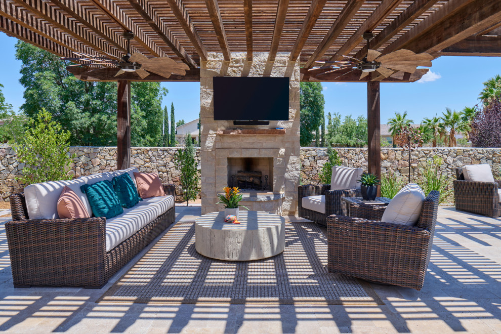 Mittelgroßer Mediterraner Gartenkamin hinter dem Haus mit direkter Sonneneinstrahlung, Natursteinplatten und Steinzaun in Sonstige